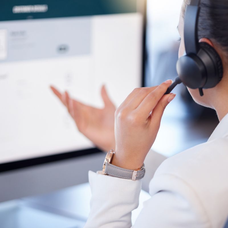 A lady in the office answering a call from her work laptop to give support to a customer.